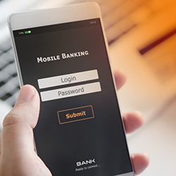 Eine Person h&auml;lt ein Smartphone mit ge&ouml;ffnetem Mobile-Banking-Login